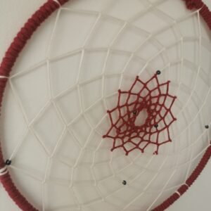 Gros plan sur le tissage artisanal en forme d'étoile rouge cerise d'un attrape-rêves fait main.