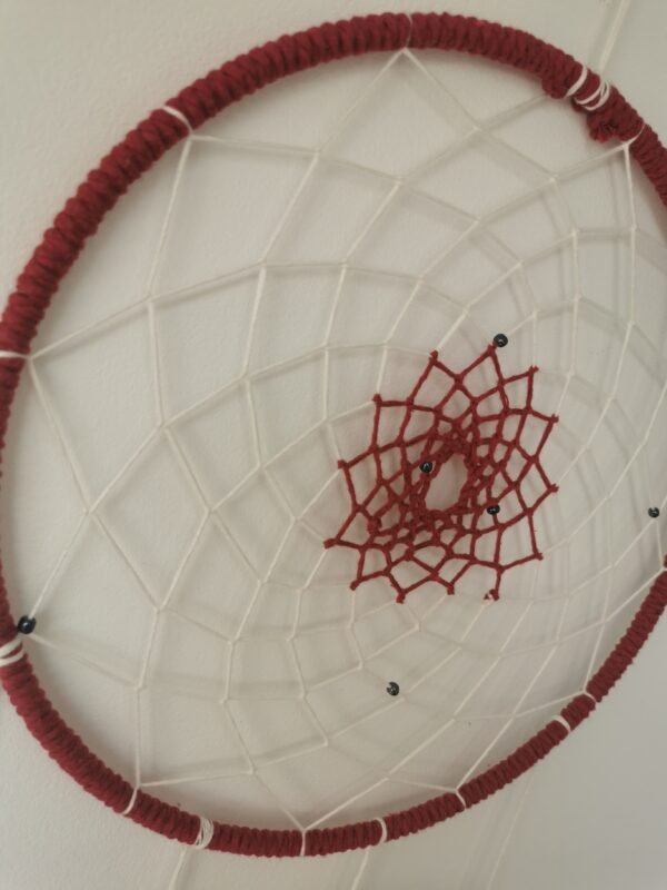 Gros plan sur le tissage artisanal en forme d'étoile rouge cerise d'un attrape-rêves fait main.