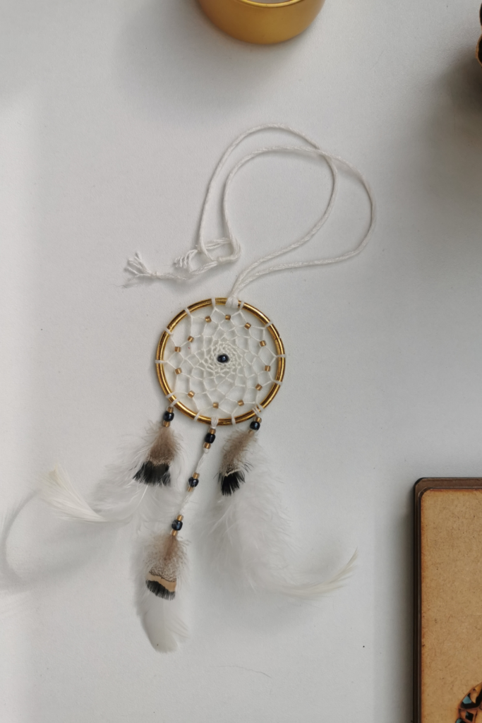 Petit attrape-rêves de rétroviseur élégant "Zéphyr" de 5 cm, fait main par Yudreami, avec un anneau doré et un tissage en fil de bambou crème.